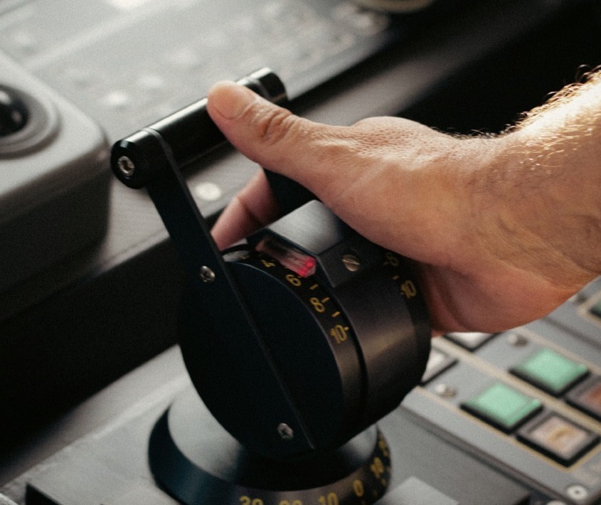 Hand on an engine control lever at the helm