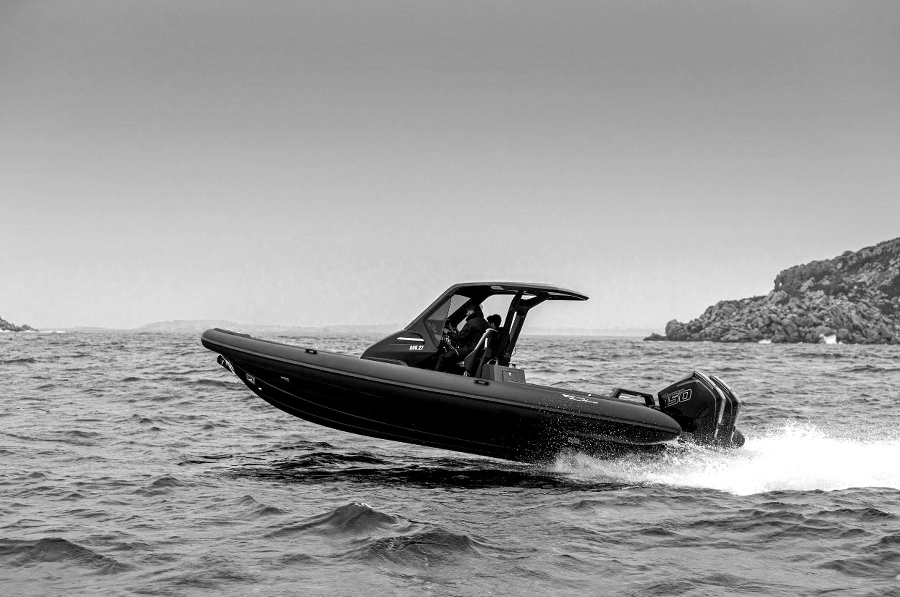 Rigid inflatable tender running off a rocky coast